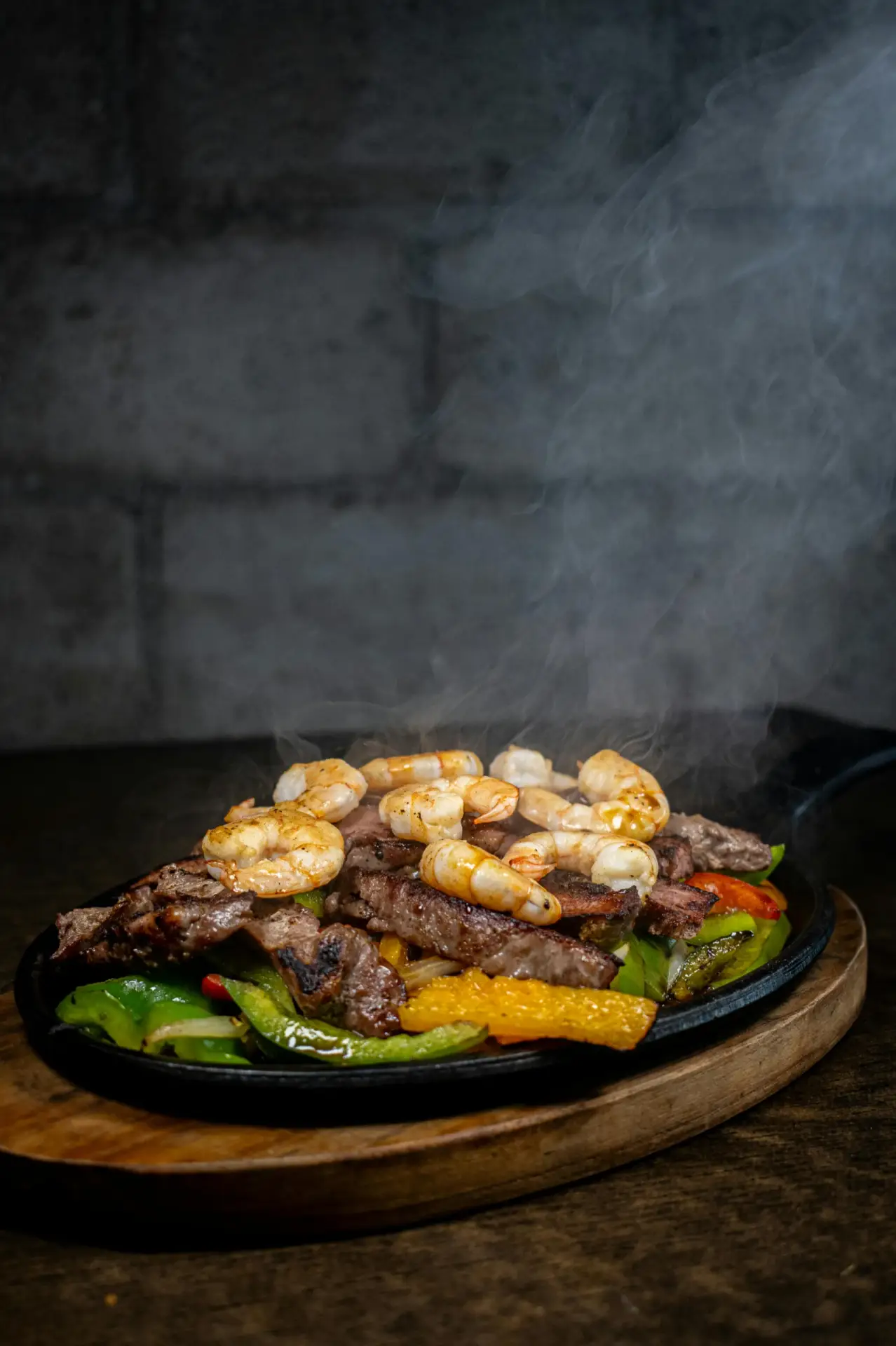 Sizzling steak and shrimp fajitas served on a hot skillet with grilled bell peppers at Don Cangrejo Bar and Grill, a Mexican restaurant known for bold flavors and authentic cuisine in Jacksonville, NC.